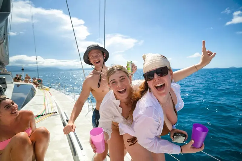 Freunde feiern an Deck bei einer Segeltour in den Whitsundays