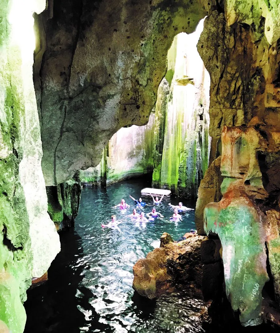 Schwimmer im Kalksteinhöhlenbecken von Sawa-i-Lau, beleuchtet durch eine Öffnung von oben