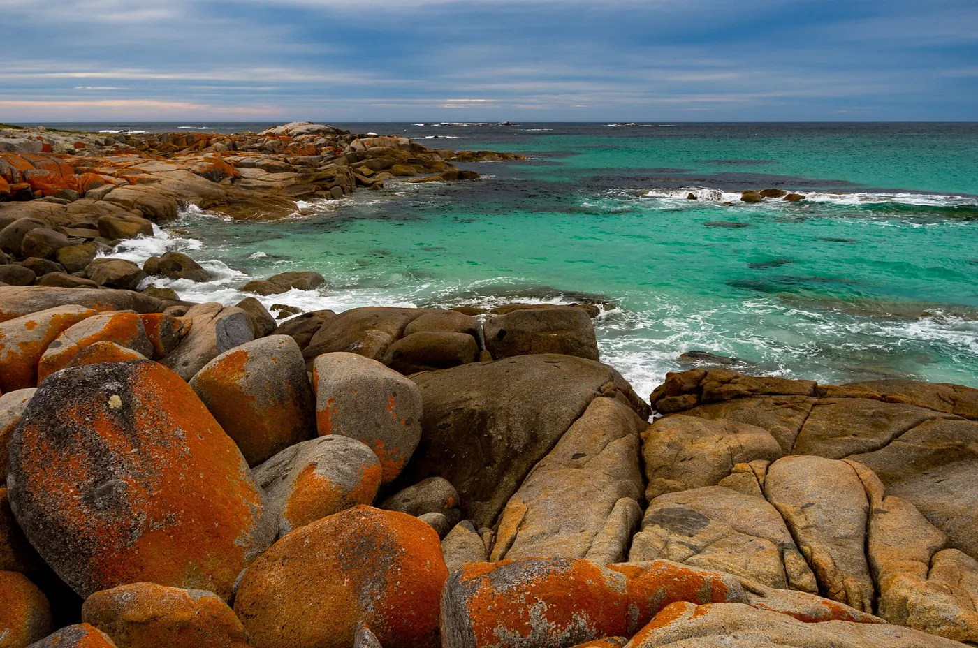 Mit orangen Flechten bedeckter Granit an der Bay of Fires